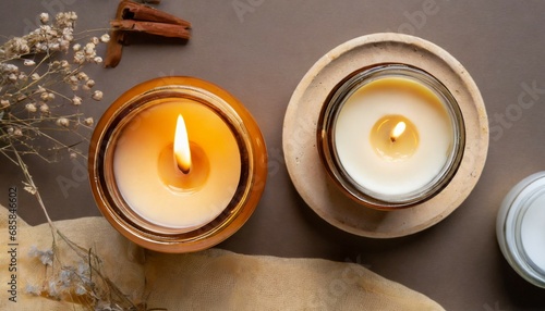 two candles burning soy way candle in an amber glass jar and a cream colored tea light over background top view generative ai photo
