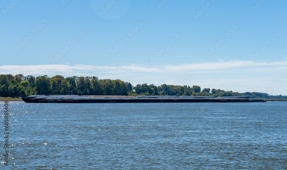 Large tug boat pushing rows of barges with grain products up the Mississippi river south of Cairo in Illinois