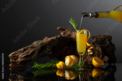 Traditional Italian liqueur Limoncello on a black reflective background. photo