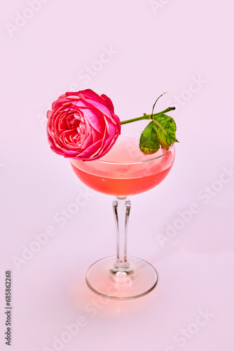 Glass with delicious sweet and sour cocktail with rose flower isolated over pink background. Concept of alcohol drinks, taste, party, celebration