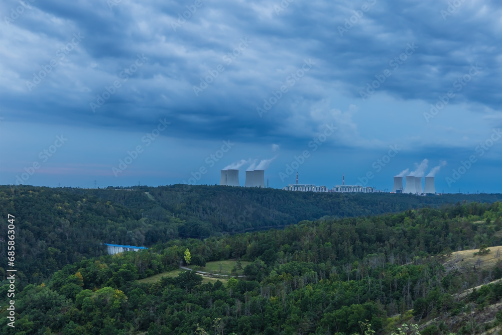 Dukovany nuclear power plant in the Czech Republic, Europe. Smoke cooling towers. There are clouds in the sky. In the foreground is the nature of the Highlands.