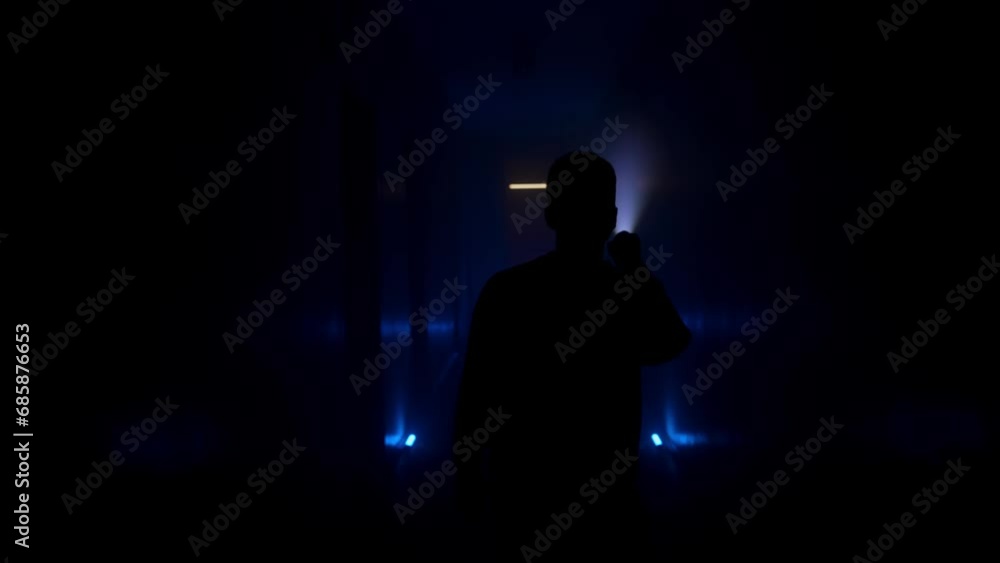 Man with a flashlight walks along a dark corridor. Back view Man with a flashlight walks along a dark corridor. Back view