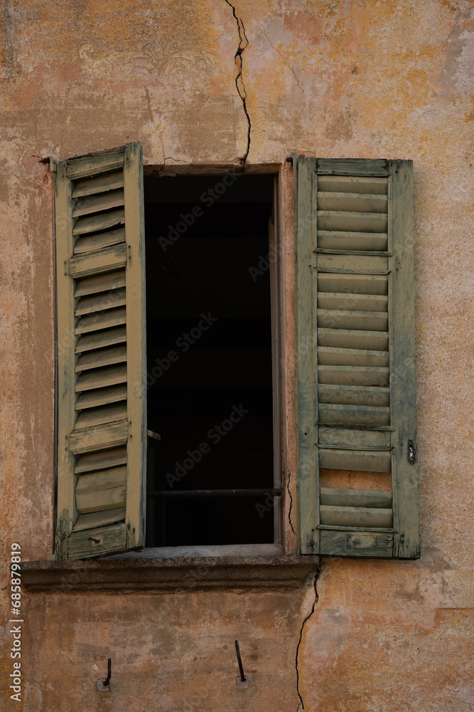 An old window in an old Italian facade wall with one shutter open