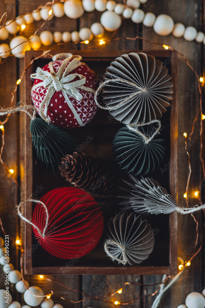 Cozy atmospheric photo, home festive atmosphere. Collection of old fashioned christmas new year foldable honeycomb toys, craft holiday decoration in vintage wooden box. Magic lights on background Cozy atmospheric photo, home festive atmosphere. Collection of old fashioned christmas new year foldable honeycomb toys, craft holiday decoration in vintage wooden box. Magic lights on background