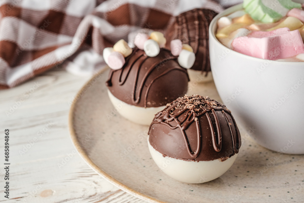 Chocolate bomb with cocoa powder and mini marshmallow to prepare a fragrant hot drink. On white wooden background. Chocolate bomb with cocoa powder and mini marshmallow to prepare a fragrant hot drink. On white wooden background.