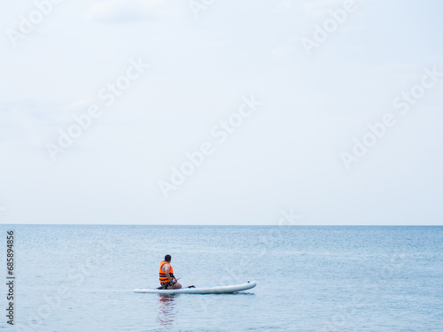 An athlete trains on a board, swims in the sea and rows. Surfing on a surfboard as a hobby.