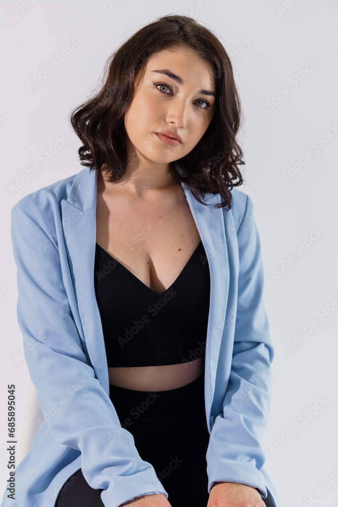 Beautiful young girl in black trousers and a blue jacket on a white background. Portrait of a beautiful young woman Beautiful young girl in black trousers and a blue jacket on a white background. Portrait of a beautiful young woman