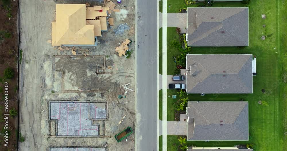 View from above of unfinished frames of private homes with wooden roofs under construction on rural street. Development of residential housing in US suburbs. Real estate market in the USA