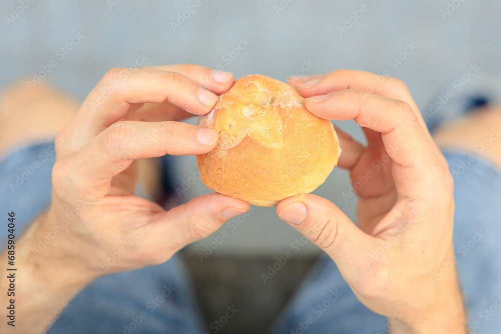 Guy's hand holds a round bun, snack and fast food concept. Selective focus on hands with blurred background