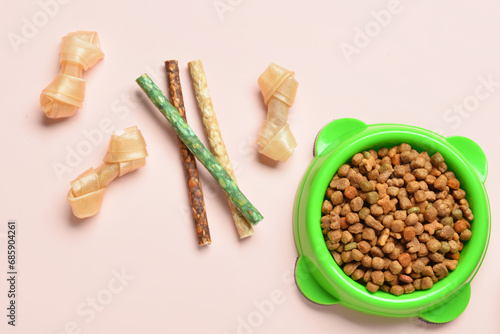 Composition with bowl of dry dog food and treats on light background