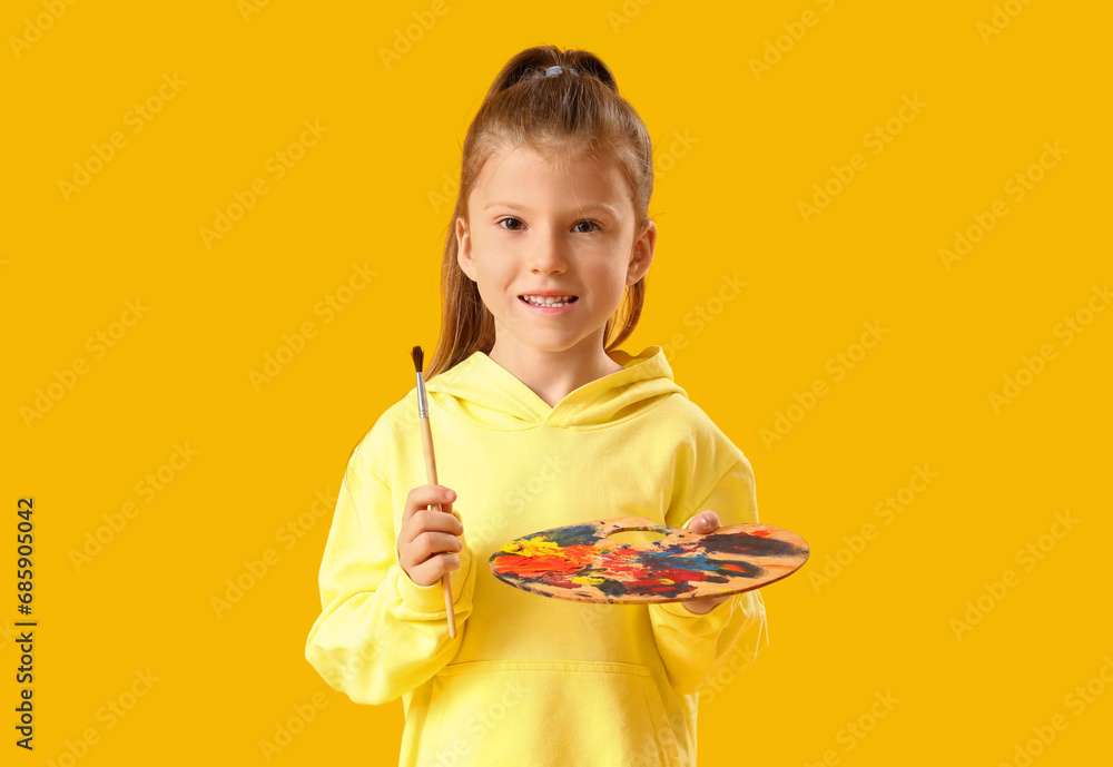 Cute little girl with paint palette and brush on yellow background Cute little girl with paint palette and brush on yellow background