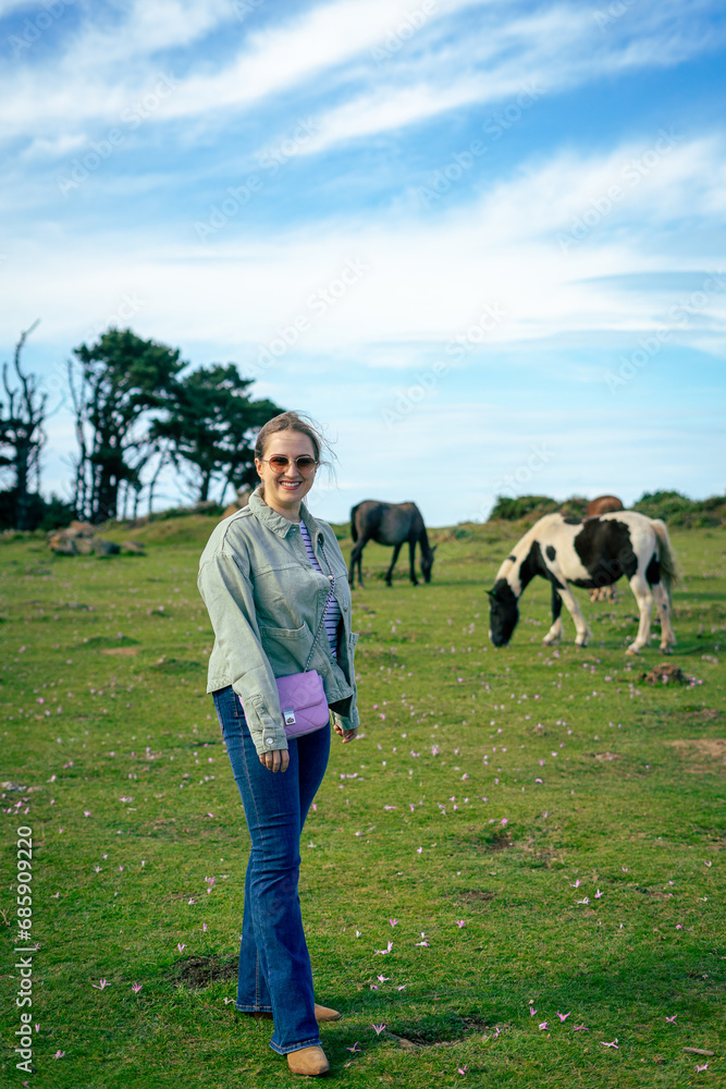 young woman posing with horses in the background in San Andres de Teixido young woman posing with horses in the background in San Andres de Teixido