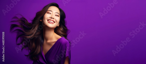 Portrait of a beautiful young Asian woman smiling on a purple background with flowing long shiny wavy hair