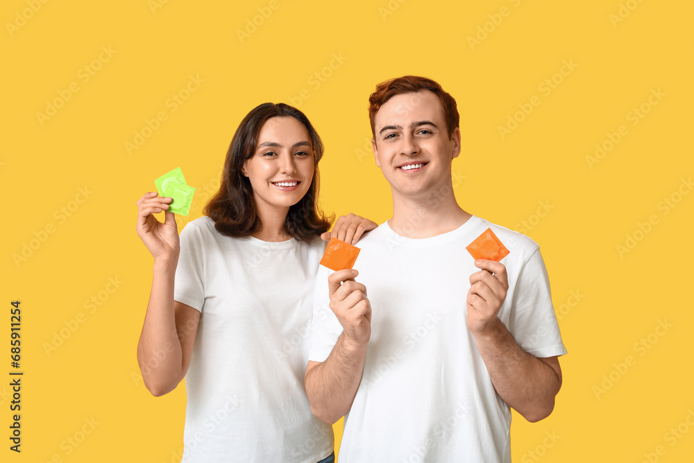 Young couple with condoms on yellow background. Safe sex concept Young couple with condoms on yellow background. Safe sex concept