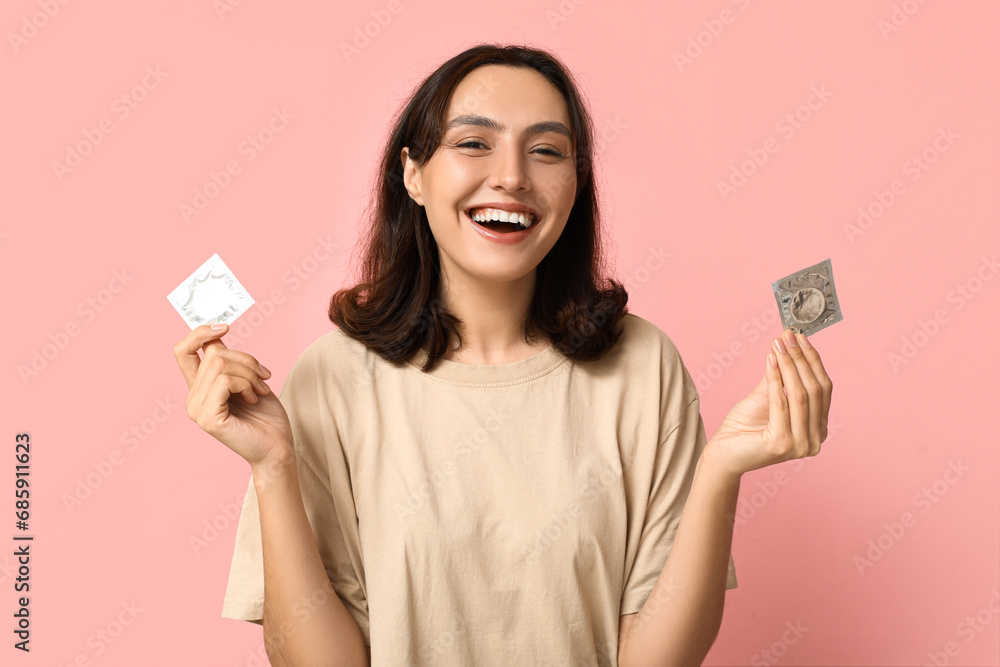 Young woman with condoms on pink background. Safe sex concept Young woman with condoms on pink background. Safe sex concept