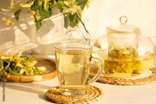 Linden flower tea in the transparent glass cup with tea spoon on a background 