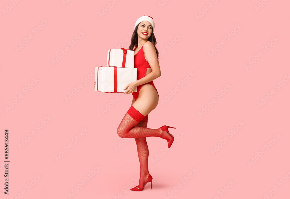 Beautiful young sexy woman in lingerie and Santa hat with Christmas gift boxes on pink background Beautiful young sexy woman in lingerie and Santa hat with Christmas gift boxes on pink background