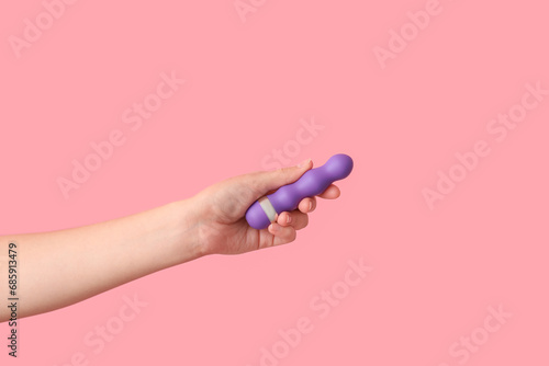 Female hand with vibrator on pink background, closeup