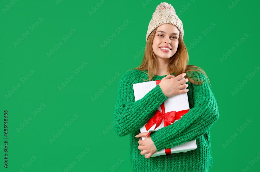 Happy young woman with Christmas gift on green background Happy young woman with Christmas gift on green background