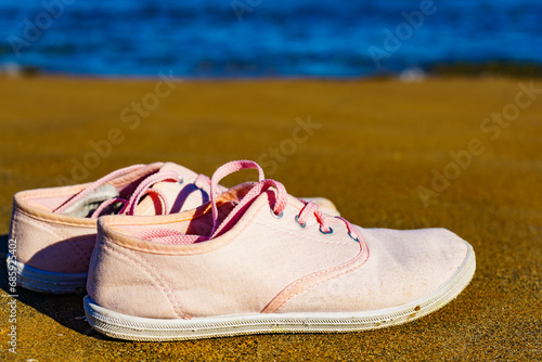Female sneakers on sand beach
