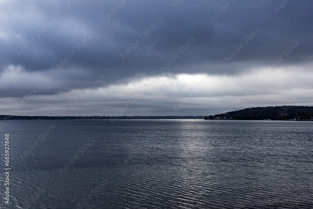 A dark blue lake on a cold, wintery day with dark rain clouds.