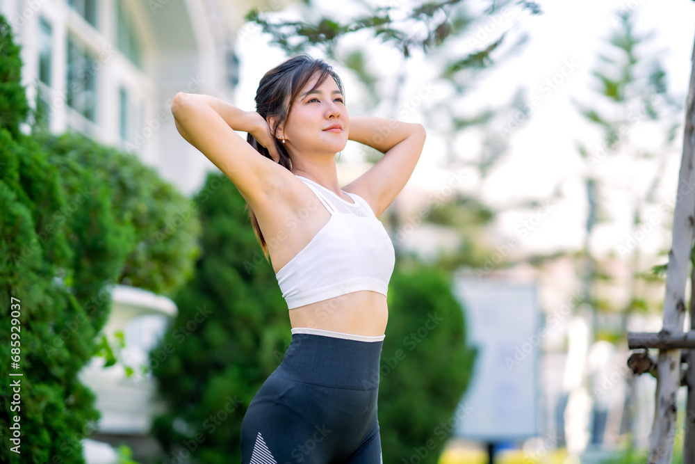 Happy slim woman wearing sportswear jogging and stretch the muscles to warm up the body in the city at sunrise. Young beautiful asian female in sports bra running outdoor.Healthy and active lifestyle Happy slim woman wearing sportswear jogging and stretch the muscles to warm up the body in the city at sunrise. Young beautiful asian female in sports bra running outdoor.Healthy and active lifestyle