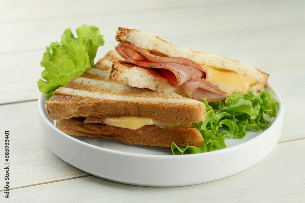 Tasty sandwiches with ham, lettuce and melted cheese on white wooden table, closeup Tasty sandwiches with ham, lettuce and melted cheese on white wooden table, closeup
