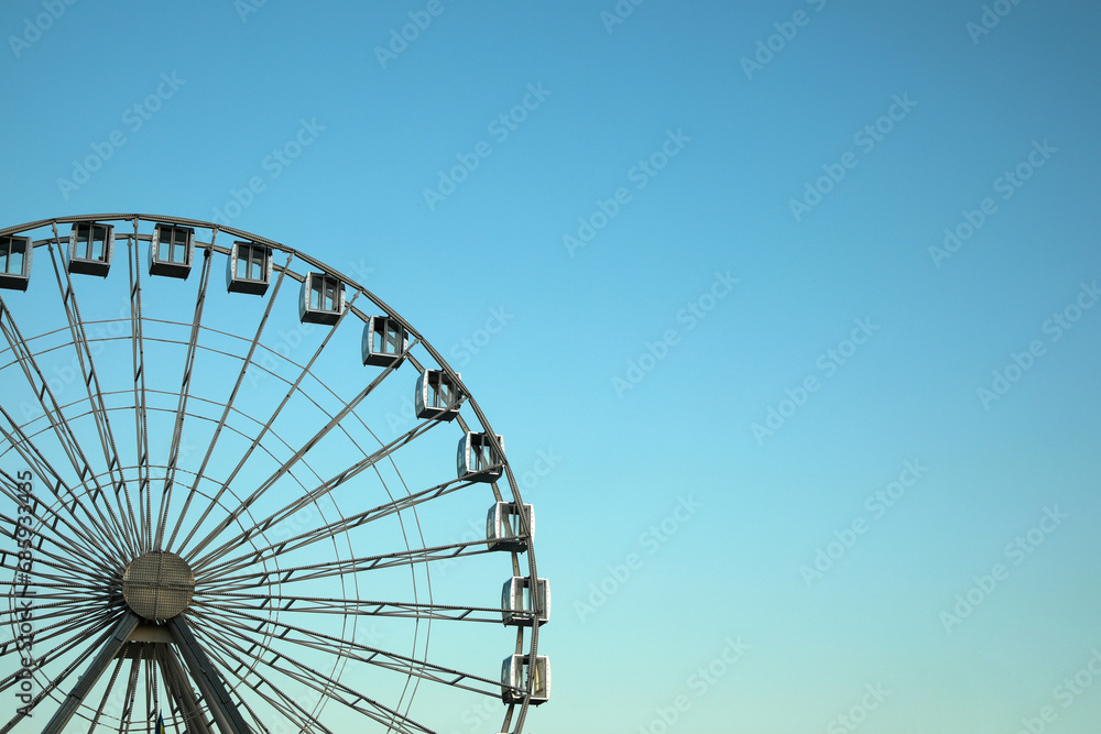 Big Ferris wheel against light blue sky. Space for text