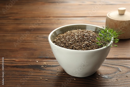 Bowl of dry seeds and fresh dill on wooden table  closeup. Space for text