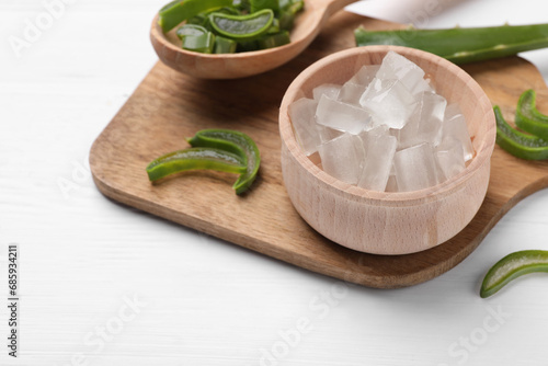 Aloe vera gel and slices of plant on white wooden table, closeup. Space for text