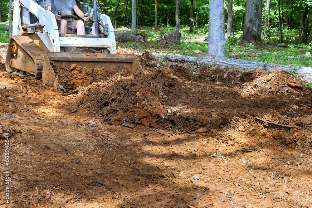 Work with earth, moving soil improving landscape of territory with mini bulldozer Work with earth, moving soil improving landscape of territory with mini bulldozer