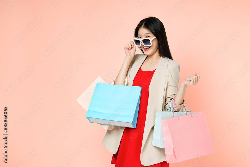 Fototapeta premium Smilling woman holding shopping bags isolated over light pink background.