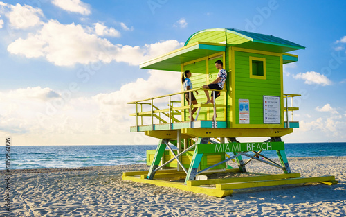 Miami Beach, a couple on the beach at Miami Florida, lifeguard hut Miami Asian women and caucasian men on the beach during sunset. man and woman watching the sunrise © Fokke Baarssen