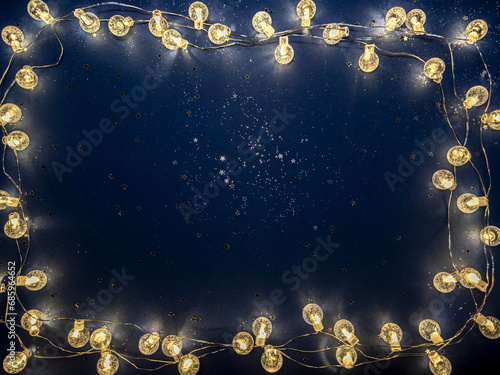 frame of glowing christmas lights on dark blue background.