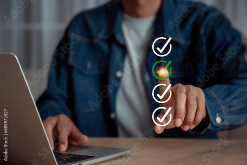 Businessman using laptop doing online checklist survey, check marks on checklist and filling online to tick check mark for quality assurance check list concept.