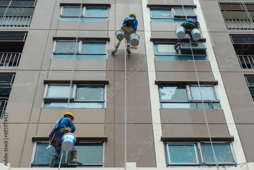Fotografie A painter is abseiling from a high-rise building