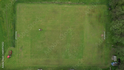 football pitch cutting machine aerial video real time, cutting green grass on a football field,sport concept,Person with pruner cutting the grass inside a football stadium with a tractor photo