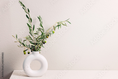 Vase with olive tree branches over the light gray wall, modern minimal design interior