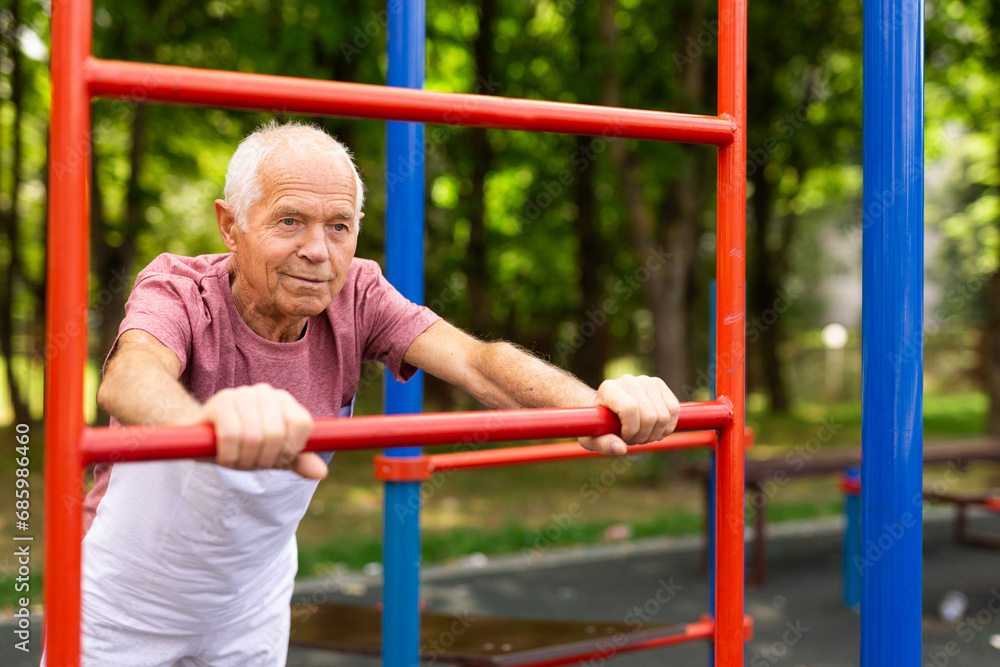 Fototapeta premium Mature man practice on the sports ground equipment in park