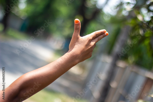 A man has two finger on his hand pointing forward and the thumb pointing up and the background blur © Rokonuzzamnan