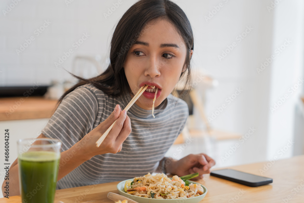 Asian Girl eating Thai food in kitchen counter Home delivery food feeling happy Asian Girl eating Thai food in kitchen counter Home delivery food feeling happy
