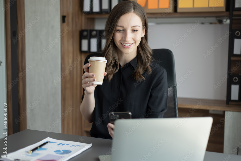 Happy businesswoman using a smartphone and sitting at desk in office. Happy businesswoman using a smartphone and sitting at desk in office.