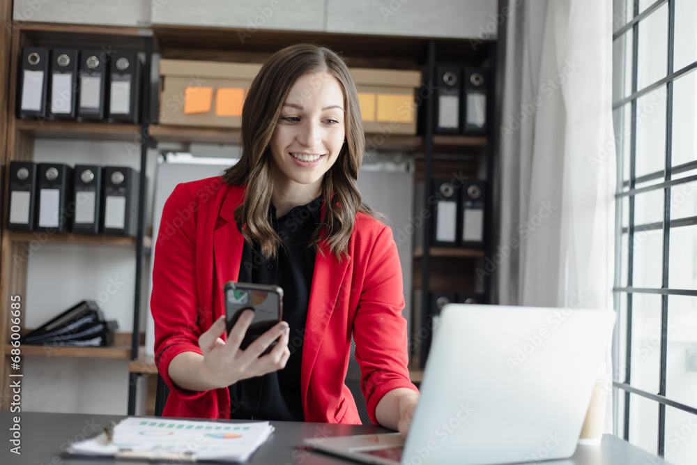 Happy businesswoman using a smartphone and sitting at desk in office. Happy businesswoman using a smartphone and sitting at desk in office.
