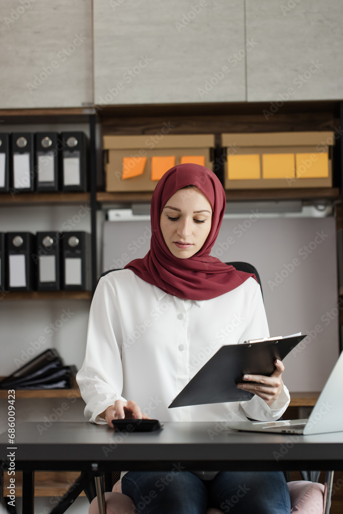 Obraz premium Happy muslim woman working at desk in office, 