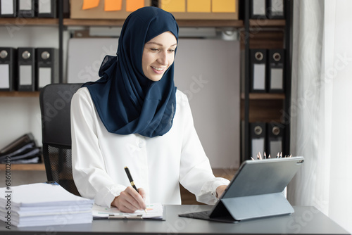 Happy muslim woman working at desk in office, 