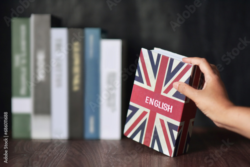 English book with hand selected from the bookshelf. Learning English fluently are benefits for connect to the new people, new bussiness, make more money, Increased brainpower and immigration . photo