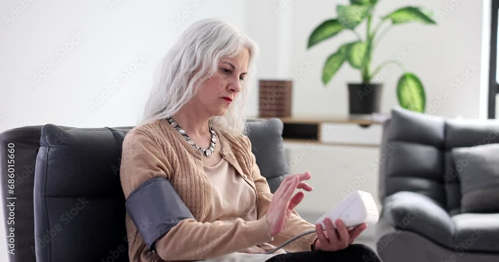 Elderly woman measuring blood pressure with electronic sphygmomanometer at home 4k movie slow motion. Diagnosis and treatment of arterial hypertension in aged patients concept Elderly woman measuring blood pressure with electronic sphygmomanometer at home 4k movie slow motion. Diagnosis and treatment of arterial hypertension in aged patients concept