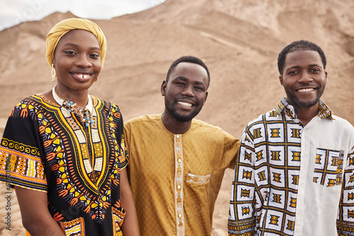 Group of young African American people wearing traditional clothing in desert, all smiling photo