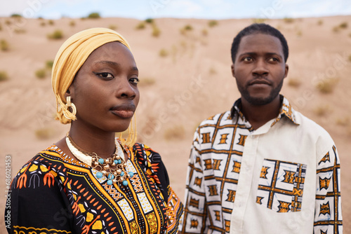 Fashion portrait of young African American couple wearing traditional clothing posing together in desert setting, copy space