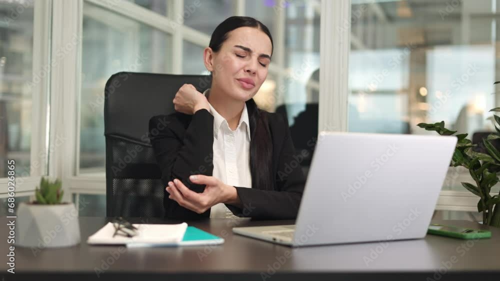 Irritated lady manager with dark hair sitting in front of digital computer and feeling severe pain in elbow indoor. Upset caucasian entrepreneur massaging hand after sedentary work in office. Irritated lady manager with dark hair sitting in front of digital computer and feeling severe pain in elbow indoor. Upset caucasian entrepreneur massaging hand after sedentary work in office.
